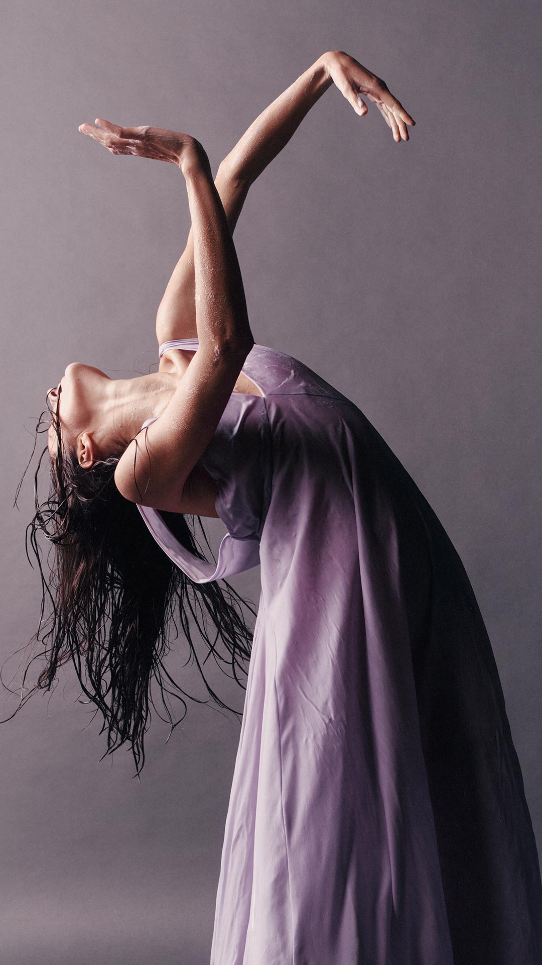 An individual wearing purple dress dancing in a purple background