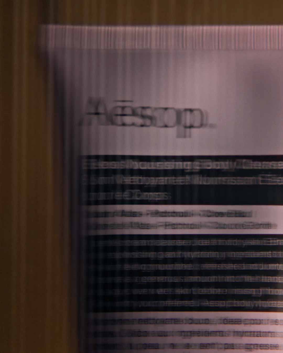 Eleos Aromatique body cleanser tube behind a textured glass