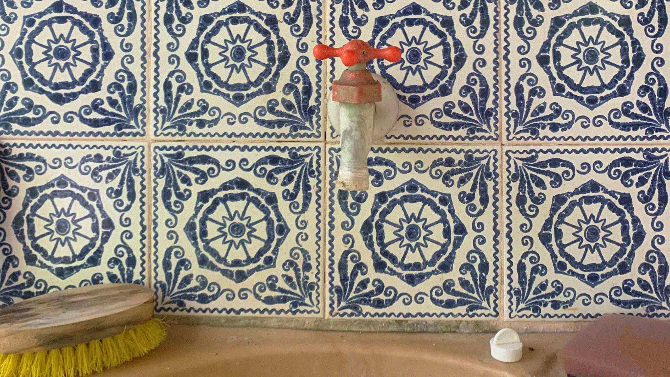 Photograph of rustic style water tap against tiled wall.