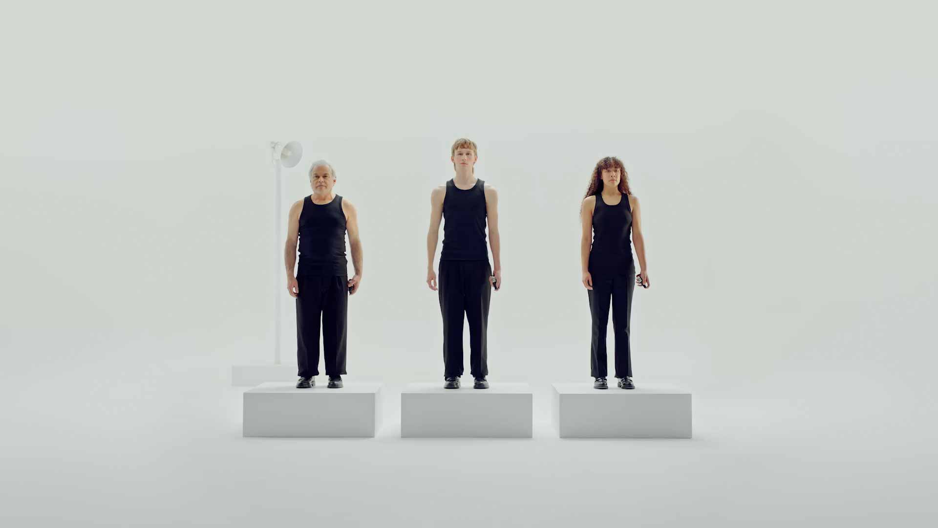 Three people standing on the white separate blocks holding Aesop deodorant
