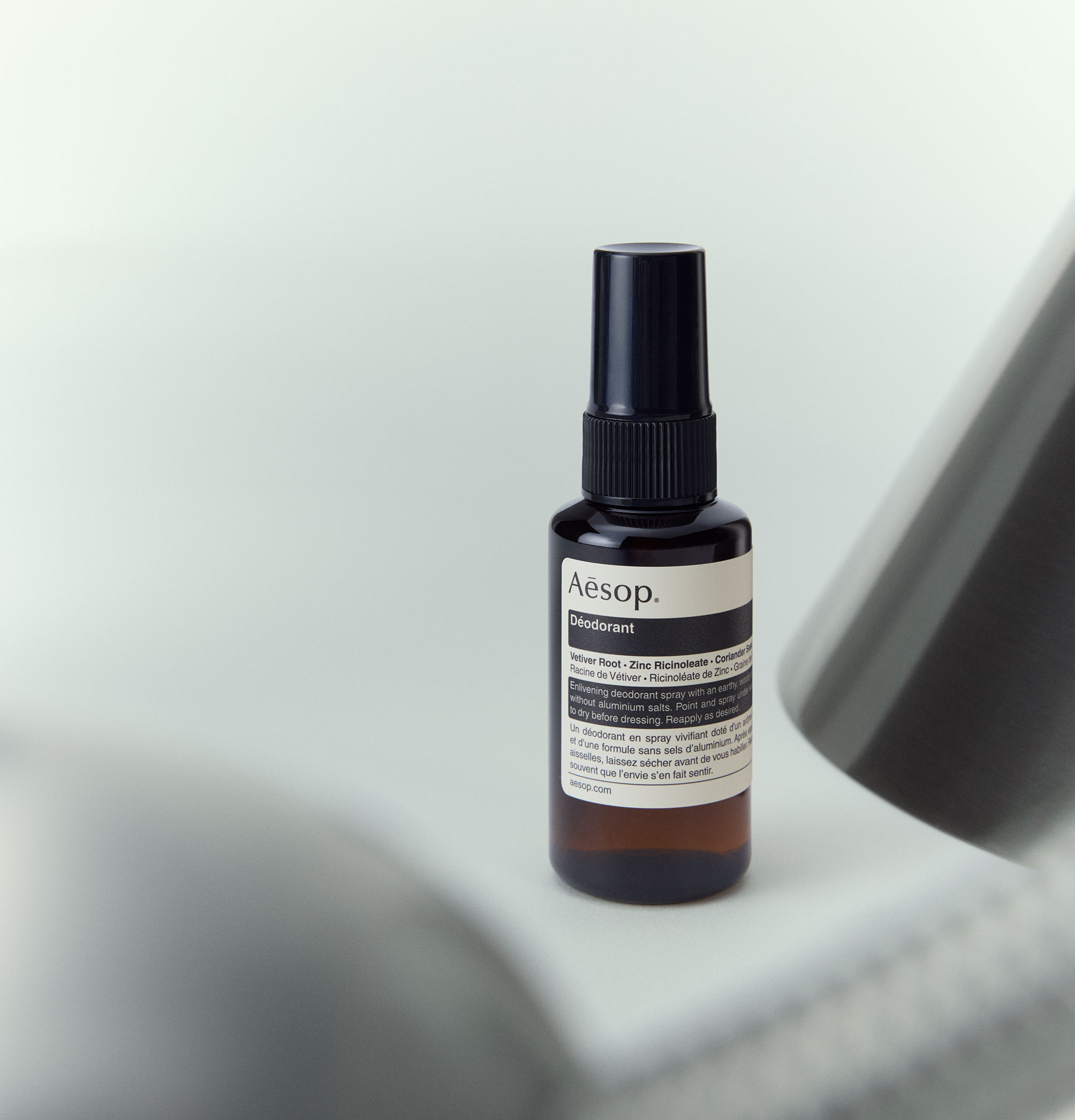 Aesop Deodorant in amber spray bottle arranged on the corner of the white desk